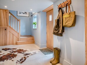 A staircase with wooden railings, a cowhide rug, a wooden door, and a wall-mounted coat rack with bags. - 1 Bed in Gloucester (oc-95793) (Tirley)