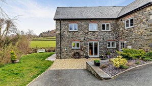 A stone building with multiple windows, a gravel driveway, and a well-maintained lawn. - 2 Bed in Llanidloes (oc-95815) (Llanidloes Without)