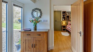 A hallway with a wooden cabinet, a mirror, and a door leading to a room with a bed and a shelf. - 2 Bed in Llanidloes (oc-95815) (Llanidloes Without)