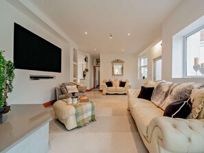 A spacious living room with a large flat-screen TV, two sofas, a coffee table, and a decorative mirror. - 4 Bed in Stranraer (oc-95819) (Portpatrick)
