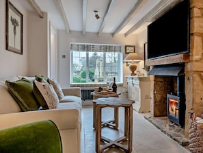 A cozy living room with a fireplace, a sofa, a table, and a window with a view of the outside. - 2 Bed in Broadway (oc-95825) (Snowshill)
