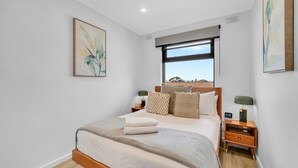 Un dormitorio con cama, ventana, ventilador de techo y obras de arte en las paredes.