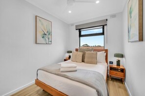 A bedroom with a bed, a window, a ceiling fan, and artwork on the walls. - Two bedroom  in Australia, Henley Beach South (Henley Beach South)