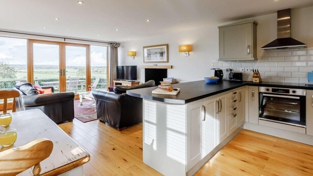 Una cocina moderna con una isla central, un área de comedor con mesa y sillas, y un ventanal con vistas.