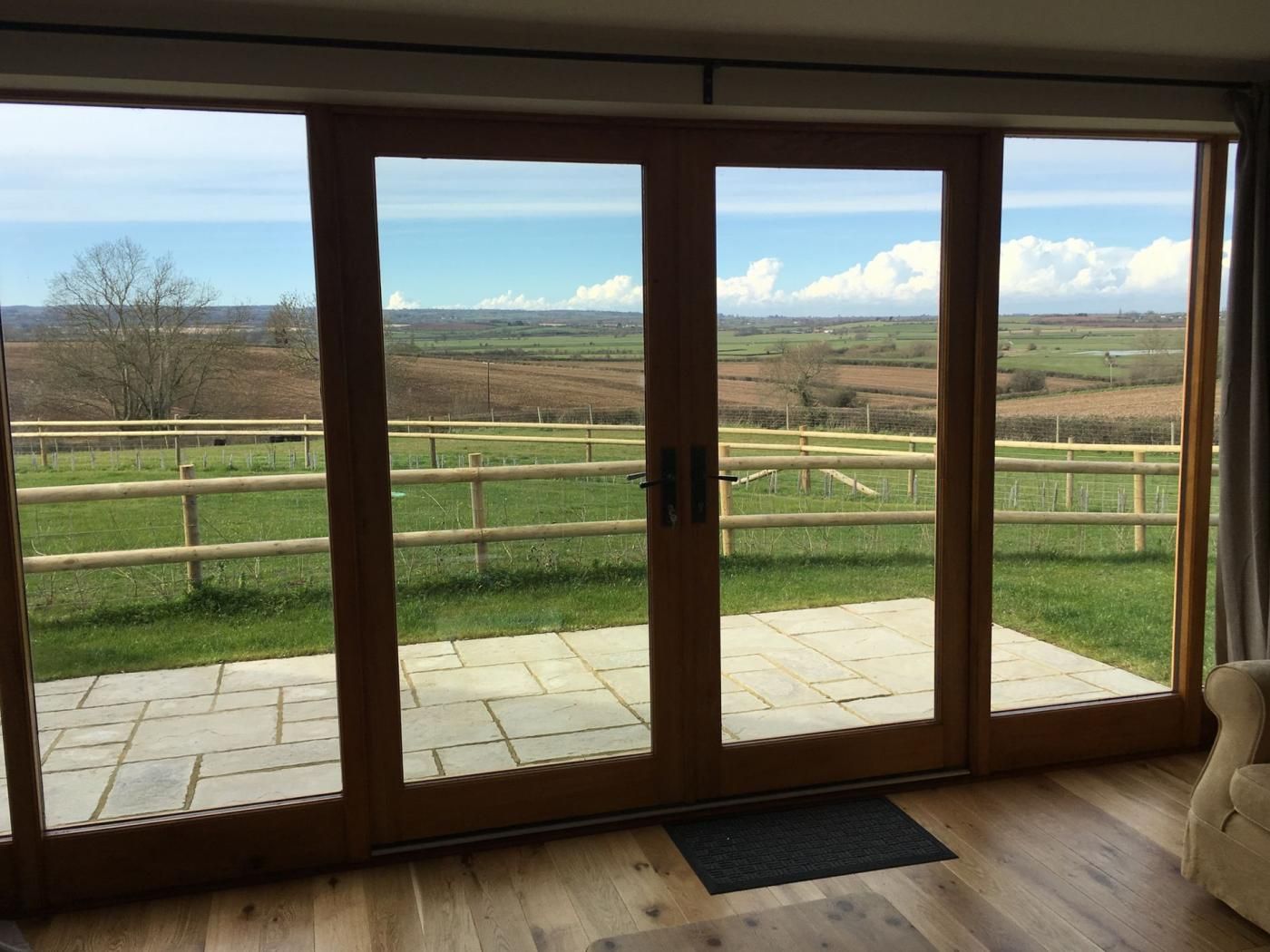 A room with a large sliding glass door leading to an outdoor area with a wooden deck and a view of a rural landscape.
