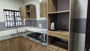 Cozinha com armários de madeira, micro-ondas embutido e janela com grades.