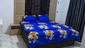 Quarto com cama, mesa de cabeceira e ventoinha no teto.