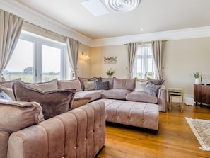 Ein geräumiges Wohnzimmer mit einem großzügigen L-förmigen Sofa, einem kleinen Beistelltisch und einer Wanddekoration.