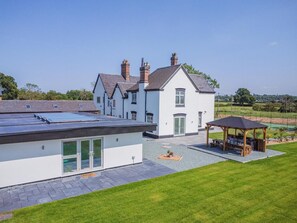 A modern house with a large patio area, a covered outdoor seating area, and a solar panel on the roof.