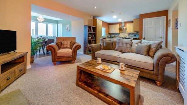 A living room with a sofa, armchairs, a coffee table, and a TV. - 2 Bed in Bonnybridge (oc-95833) (Bonnybridge)