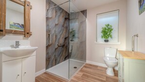 A modern bathroom with a glass shower enclosure, a white sink, a toilet, and a window with a plant. - 2 Bed in Bonnybridge (oc-95833) (Bonnybridge)