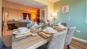 A dining area with a table set for four, a chandelier, and a painting on the wall. - 2 Bed in Bonnybridge (oc-95833) (Bonnybridge)