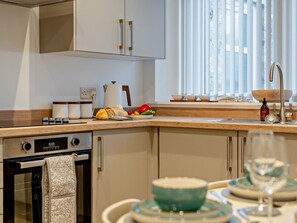 Eine moderne Küche mit Backofen, Kaffeemaschine und einem Essbereich mit Tisch für zwei Personen.