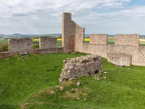 Eine historische Steinarchitektur mit Ruinen, grüner Landschaft und weitläufigen Feldern.