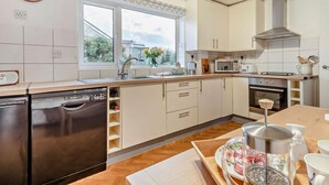 A modern kitchen with a dishwasher, oven, microwave, and a large window. - 3 Bed in Keswick (oc-95858) (Keswick)