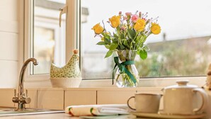 A kitchen with a window, a vase of flowers, a kettle, and a teapot on the counter. - 3 Bed in Keswick (oc-95858) (Keswick)