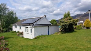 A single-story house with a sloped roof, solar panels, and a small garden. - 3 Bed in Keswick (oc-95858) (Keswick)
