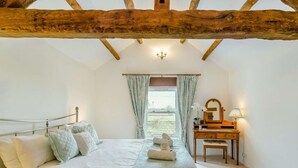 Een slaapkamer met een bed, een kaptafel, een spiegel en een raam met gordijnen.