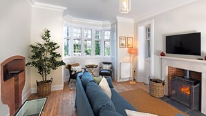 Ein gemütliches Wohnzimmer mit Kamin, großem Fenster und Fernseher.