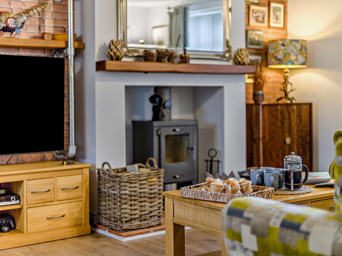 A living room with a television, a fireplace, a coffee table with pastries, and a lamp.