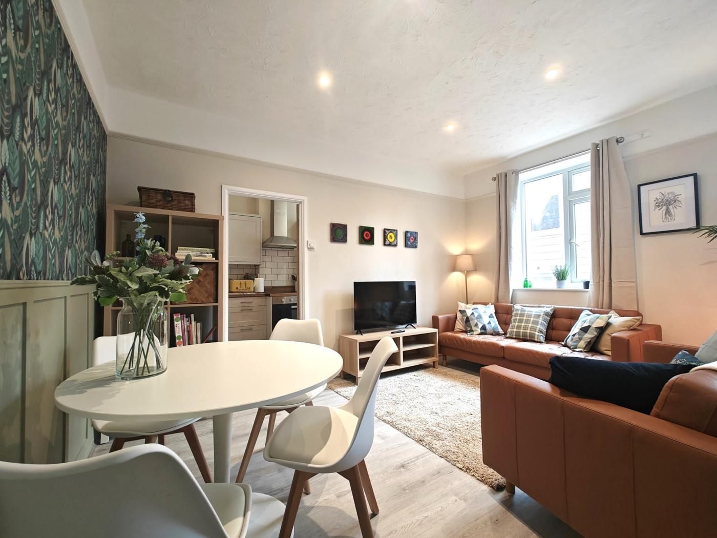 A living room with a sofa, TV, and a dining area with chairs and a table.