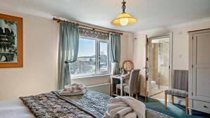 Ett hotellrum med en stor säng, ett skrivbord med en stol, utsikt över omgivningarna och en garderob.