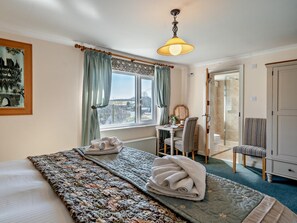 Ein Hotelzimmer mit einem großen Bett, einem Schreibtisch mit Stuhl, Blick ins Freie und einem Kleiderschrank.