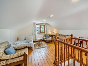 A cozy loft bedroom with a wooden floor, a bed, a sofa, a chair, a table, and a foosball table. - 3 Bed in Wigton (oc-95374) (Uldale)