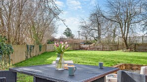 Een terras met rieten meubels, een tafel en een bloevas.