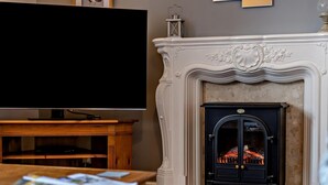 A living room with a fireplace, a television, and a wooden entertainment unit. - 2 Bed in Ambleside (oc-95914) (Hawkshead)