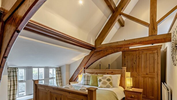 A bedroom with a wooden bed, a nightstand, a wardrobe, and a window with curtains. - 2 Bed in Ambleside (oc-95914) (Hawkshead)