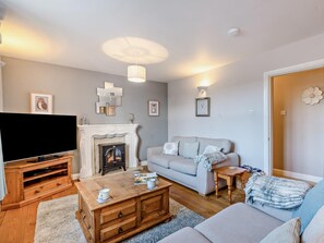 Ein Wohnzimmer mit Kamin, Sofa, Couchtisch und Fernseher.
