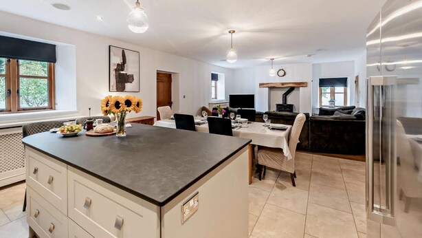 A modern kitchen with a central island, dining area, and a built-in oven. - 4 Bed in Ilfracombe (oc-95899) (Berrynarbor)
