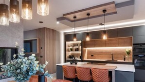 A modern kitchen with a central island, pendant lighting, and a dining area with a wooden table and chairs. - 4 Bed in Morpeth (oc-95889) (Amble)