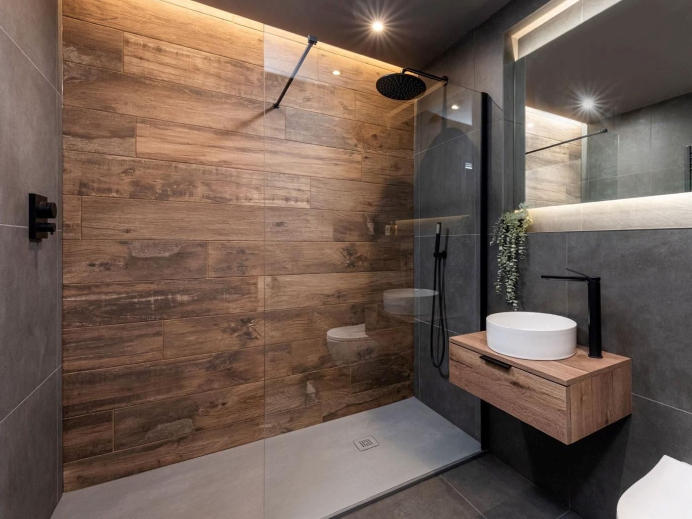 A modern bathroom with a wooden wall, a glass shower enclosure, and a wooden vanity with a sink.