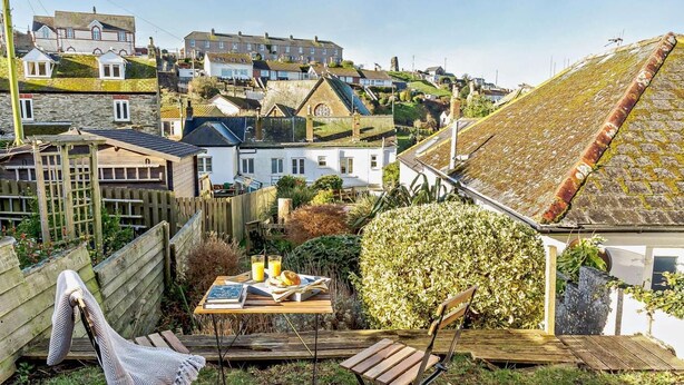 A residential area with houses, a wooden deck, and a table with books and drinks. - 2 Bed in Fowey (oc-91015) (Polruan)