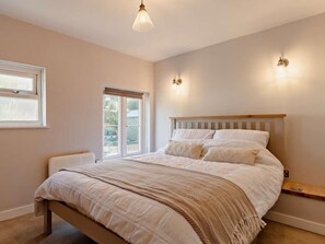 Ein Schlafzimmer mit einem Bett, einem Fenster, einer Tür und einer Wandleuchte.