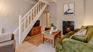 A living room with a staircase, a fireplace, and a green sofa. - 2 Bed in Fowey (oc-91015) (Polruan)