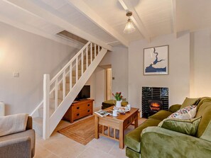 Ein Wohnzimmer mit Treppe, Kamin und einem grünen Sofa.