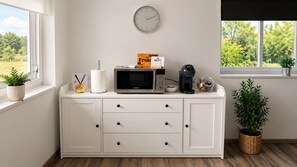 A white cabinet with a microwave, a box labeled 'Front WiFi,' and a clock on the wall.