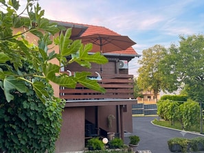 A modern building with a sloped roof, a covered outdoor seating area, and a paved driveway.