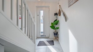 A hallway with a white door, a potted plant, and a wall-mounted sign. - 3 Bed in Llandudno (oc-95068) (Llandudno)