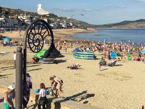 A beach with a large seagull sculpture, people sunbathing, and tents set up. - 2 Bed in Honiton (oc-52420) (Honiton)