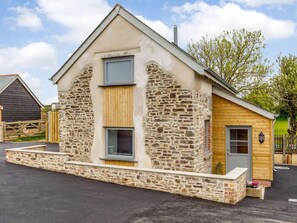 A stone building with a wooden door, a window, and a small porch area. - 1 Bed in Umberleigh (oc-82998) (Atherington)