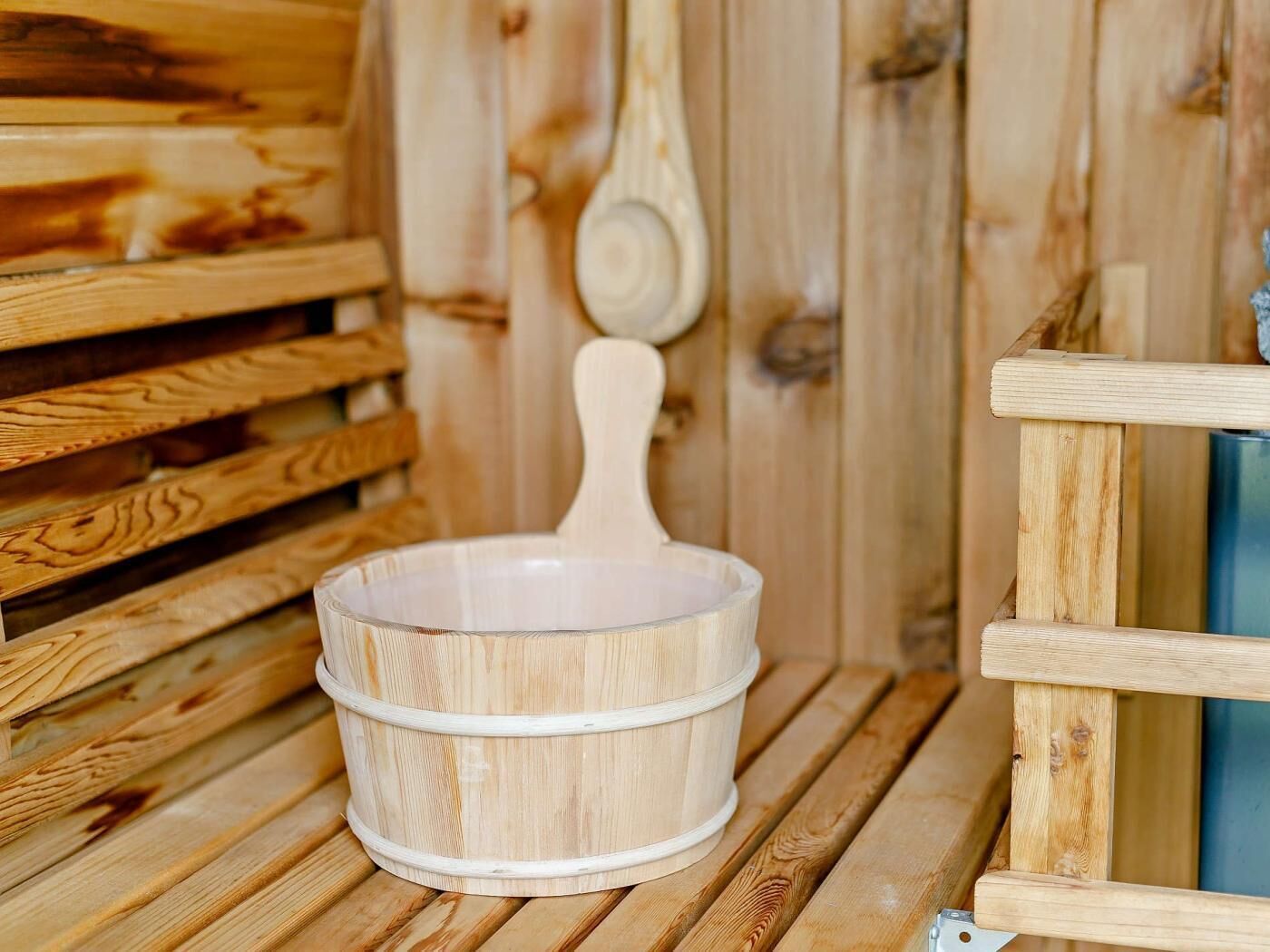 A wooden sauna with a wooden bench and a wooden bowl.