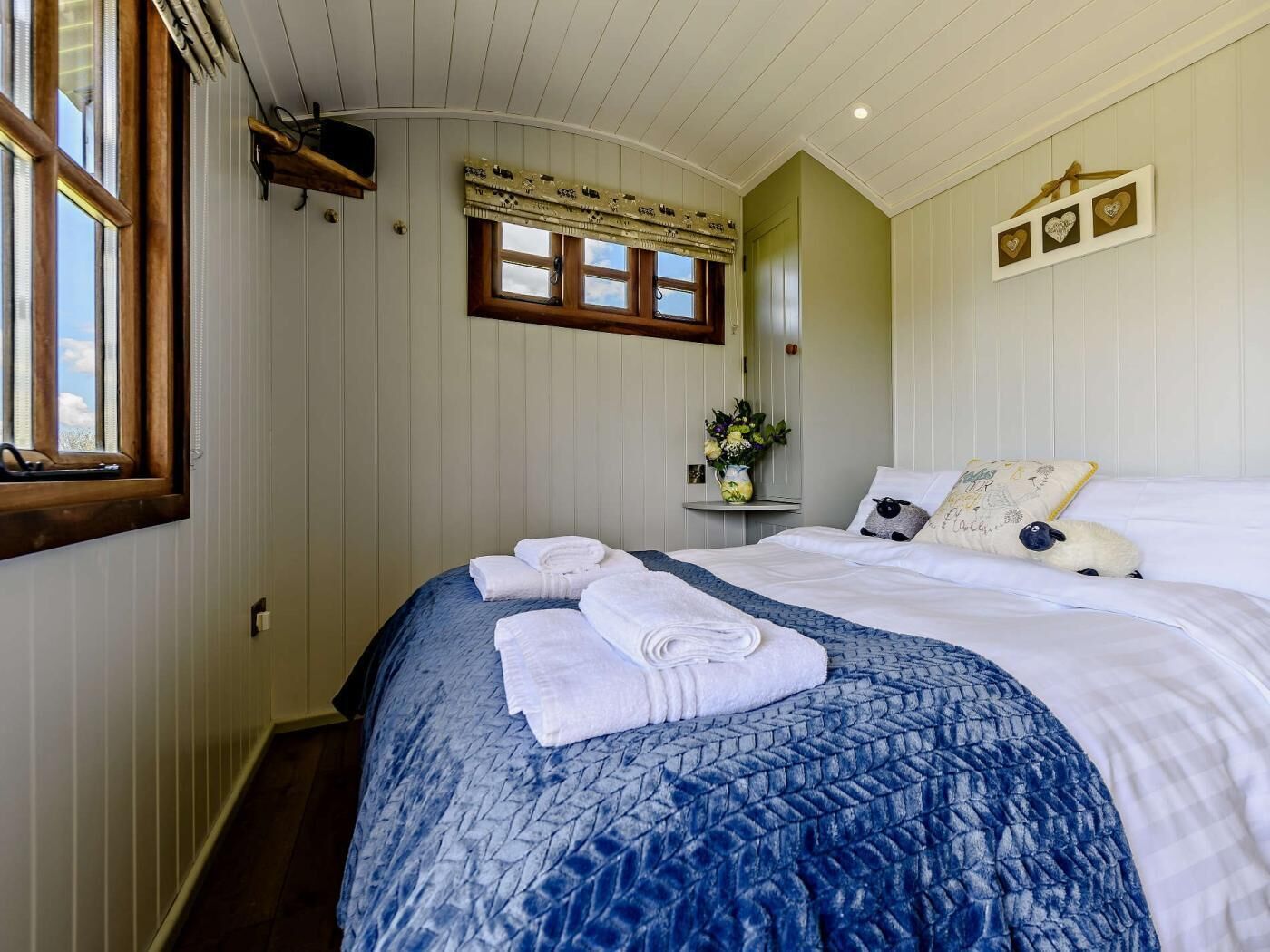 A bedroom with a bed, a window, a wall-mounted shelf, and a wall decoration.