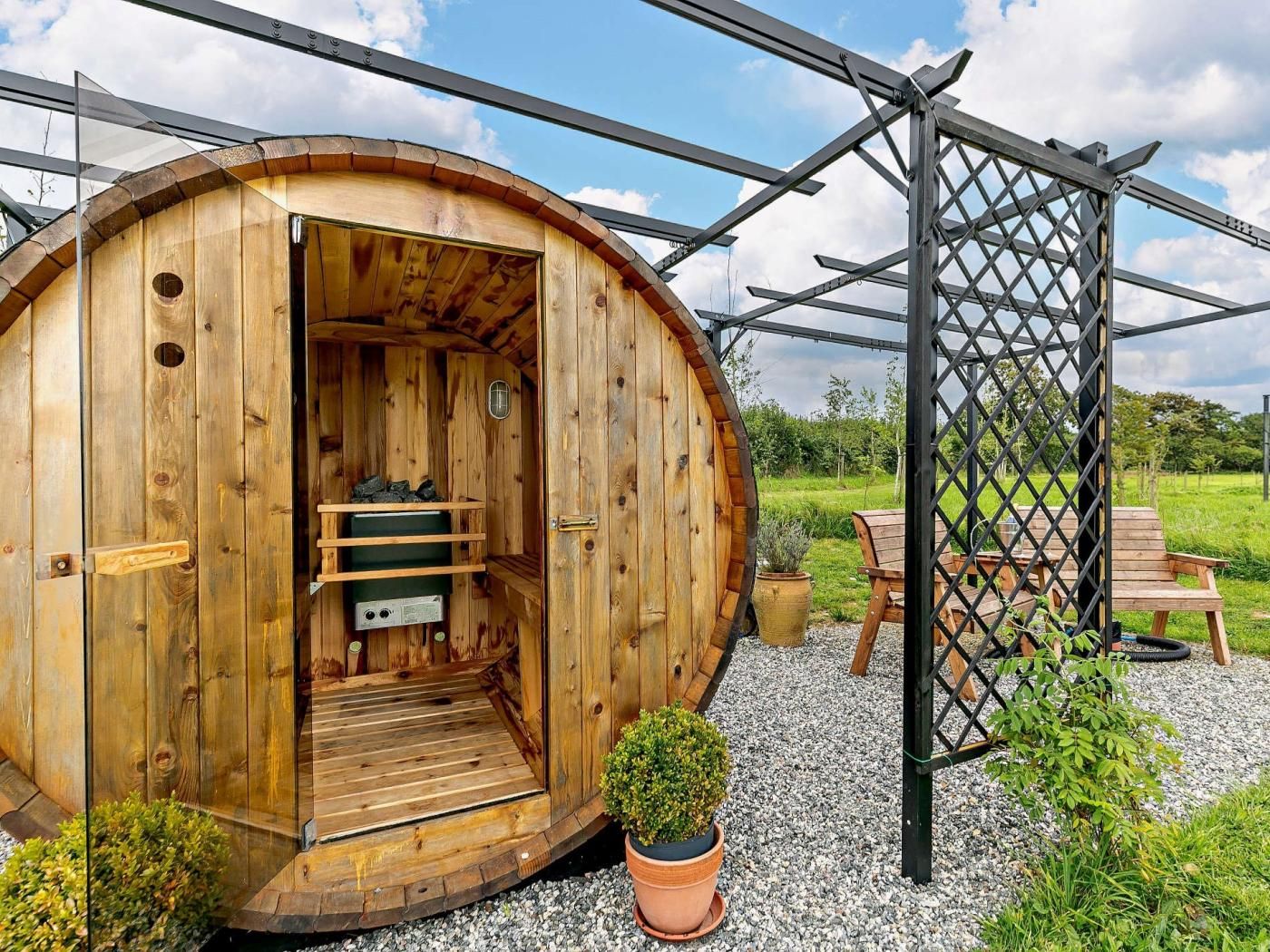 A wooden cabin with a door open, revealing a bench and a small table inside.