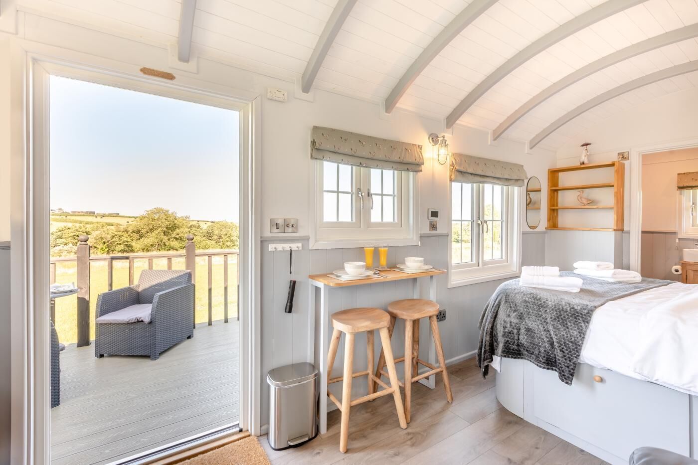 A cozy interior with a balcony, a small kitchen area, and a bed.