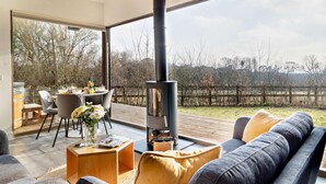 A modern living room with a large window, a sofa, a coffee table, and a fireplace. - 2 Bed in Colchester (oc-95941) (East Bergholt)