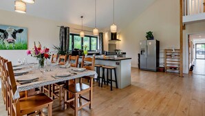A modern kitchen with a central island, wooden dining table, and chairs. - 5 Bed in Dulverton (oc-87003) (Morebath)